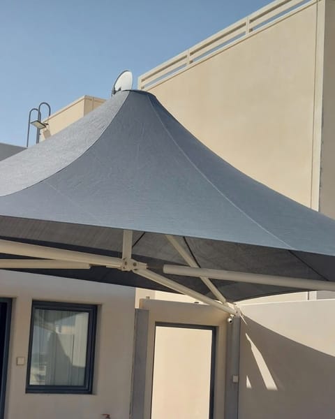 Grey conical canopy peak against a building wall