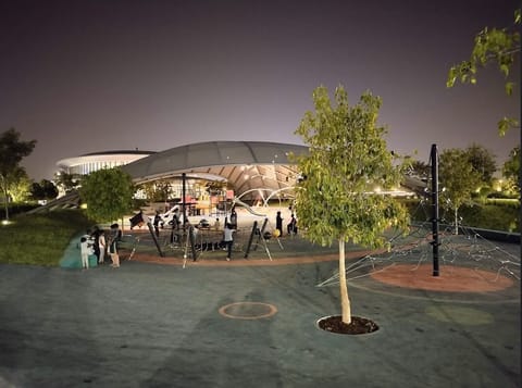 Free-form tensile canopy lit at night above a play area