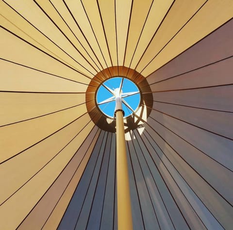 Looking up into a conical canopy at its central mast and crown ring