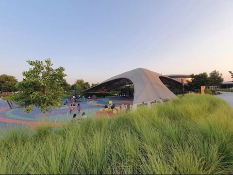 Shell-shaped tensile canopy over a park playground at dusk