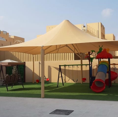 Conical sand shade over a garden play set on artificial grass
