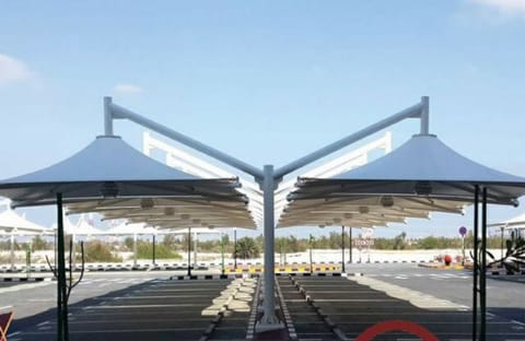 Twin cantilever car parking shades with dark membranes over marked bays