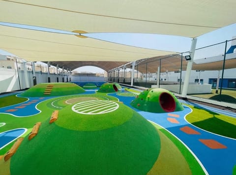 Large shade sails over a school play deck with green mounds